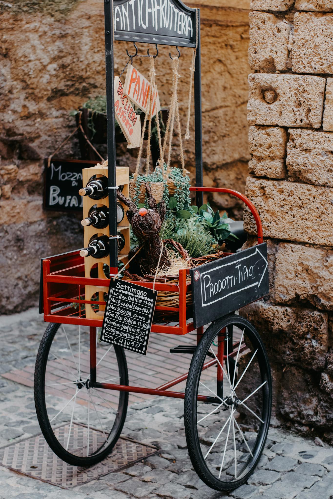 Charming Italian street food cart with wine, herbs, and local products on display.