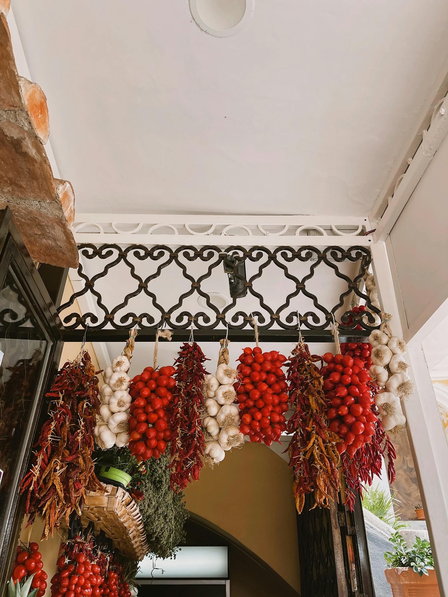 Colorful hanging tomatoes, garlic, and herbs at a local market in Amalfi, Italy.